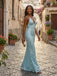 Woman in a light blue sequin dress standing on a cobbled street with flowers and buildings in the background.
