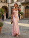Woman in a pink dress standing in an old-world street with people and buildings in the background.