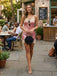 Woman in a pink dress standing on a sidewalk with outdoor seating in the background