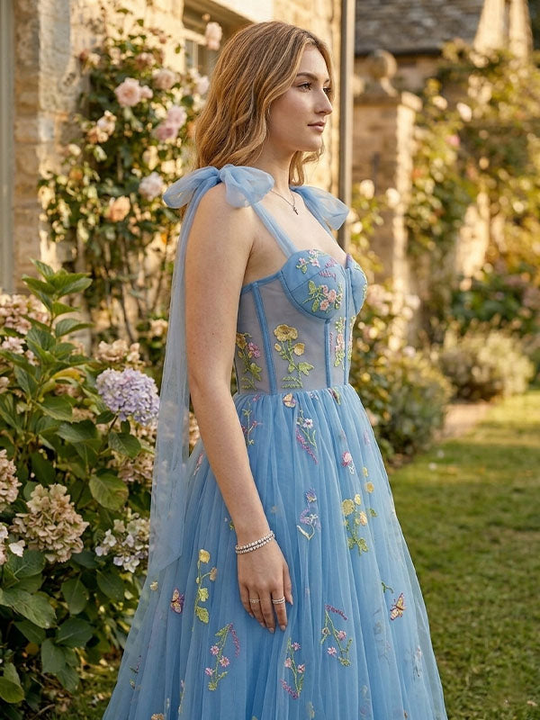 Woman in a blue embroidered dress standing in a garden