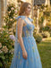 Woman in a blue embroidered dress standing in a garden