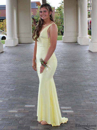 Woman in a light yellow evening gown standing outdoors with classical architecture in the background