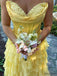 Yellow lace dress with ruffled layers held by a person outdoors.