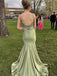 Person in a light green prom dress standing outdoors on grass with other people in the background.